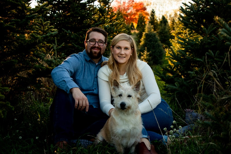 Happy couple with white dog in autumn foliage during Madison Wisconsin portrait session