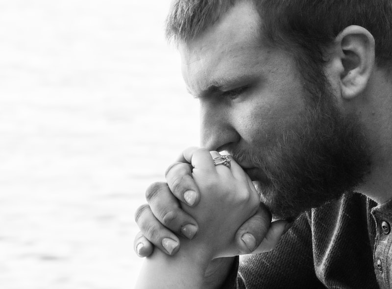 Intimate black and white event portrait of contemplative man with clasped hands in Madison, Wisconsin