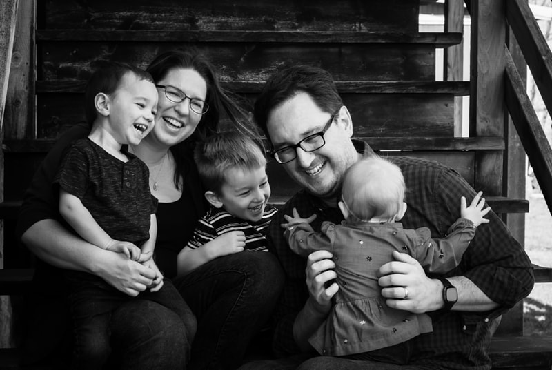 Joyful family of five laughing together on wooden stairs during Madison, Wisconsin family portrait session