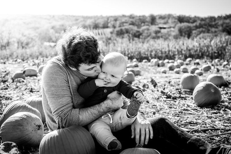 Father and toddler sharing tender moment at pumpkin patch family portrait session in Madison, Wisconsin