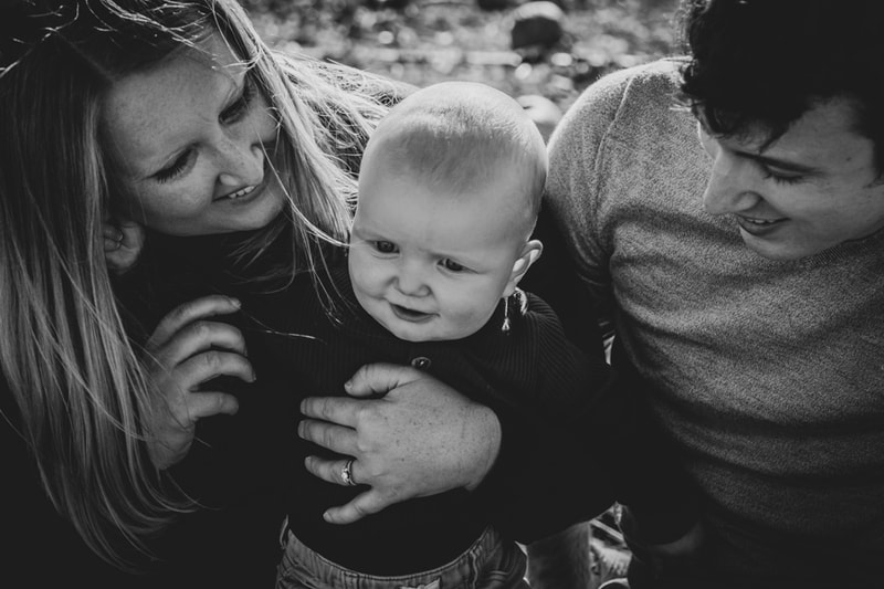 Joyful family embraces their smiling baby during intimate portrait session in Madison, Wisconsin
