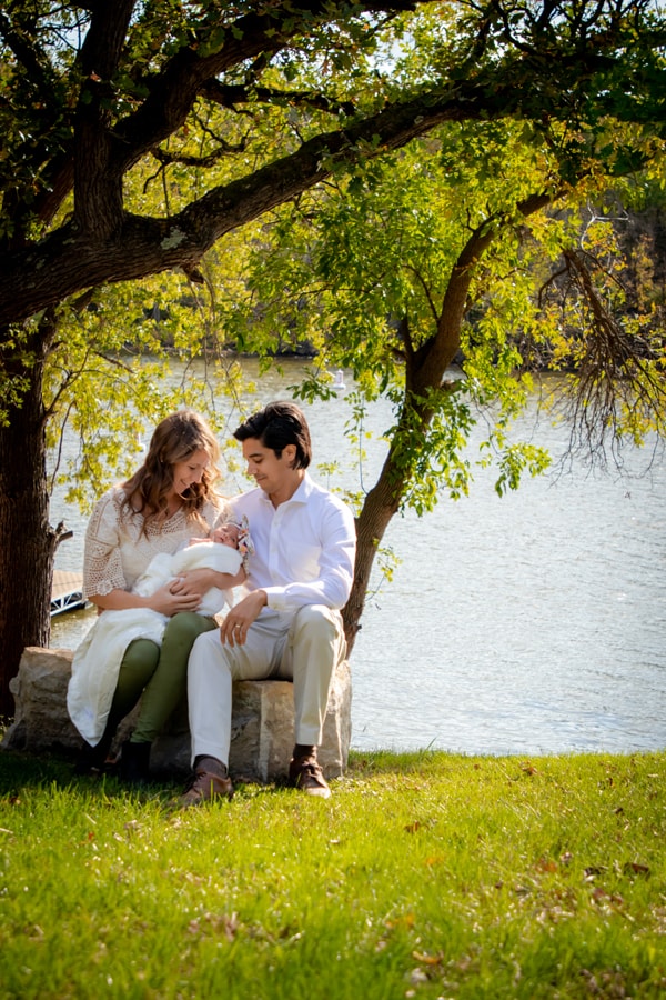 Expecting couple shares tender moment under willow tree during lakeside family portrait session in Madison, Wisconsin