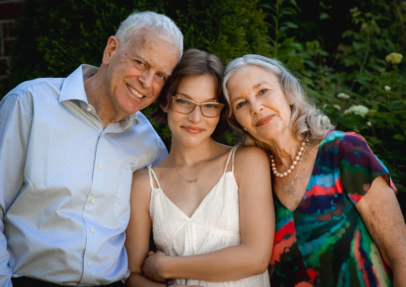 Three-generation family embracing warmly in lush garden setting, Madison Wisconsin family portrait photography