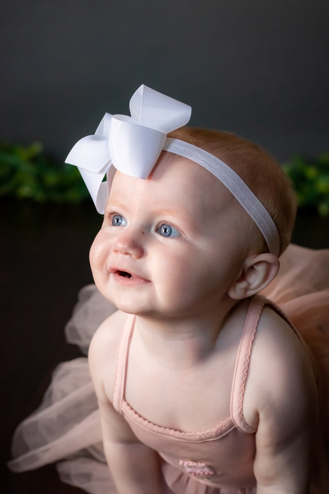 Sweet baby girl with white bow headband during milestone portrait session in Madison, Wisconsin