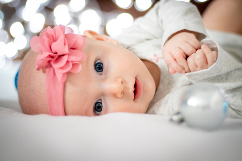 Sweet baby girl with pink flower headband smiling during milestone portrait session in Madison, Wisconsin