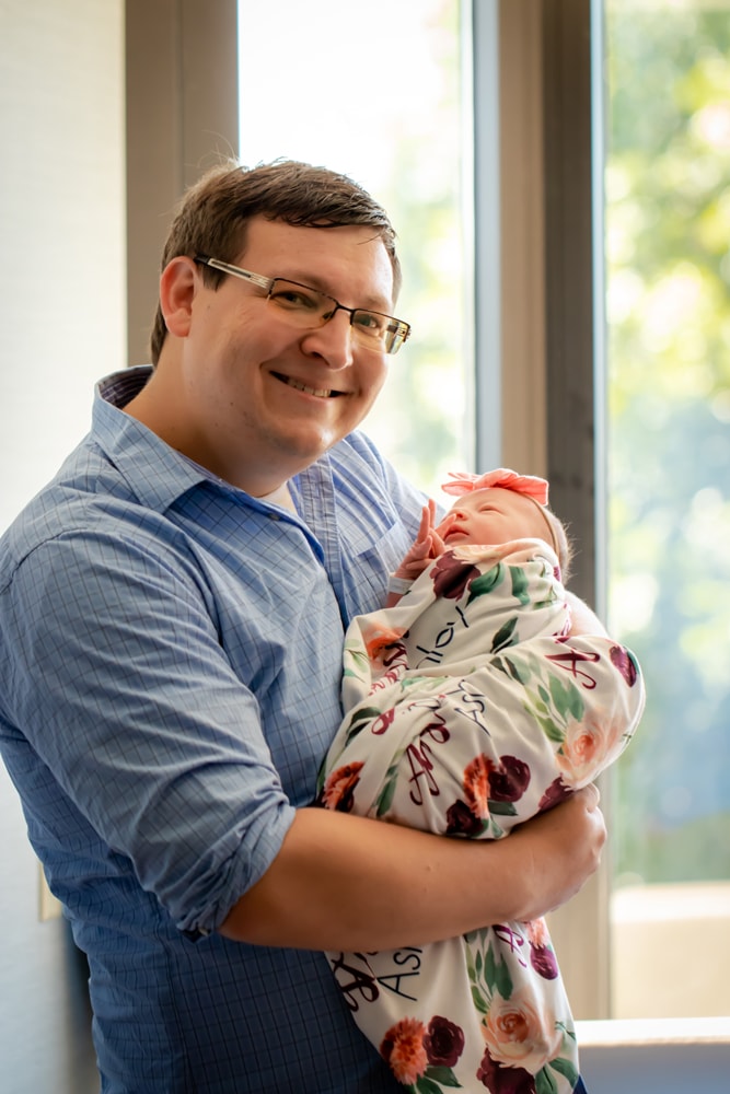 Loving father cradles swaddled newborn in tender Madison, Wisconsin newborn portrait session