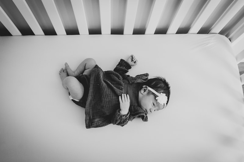 Peaceful sleeping newborn in cozy sweater captured in serene black and white portrait, Madison Wisconsin