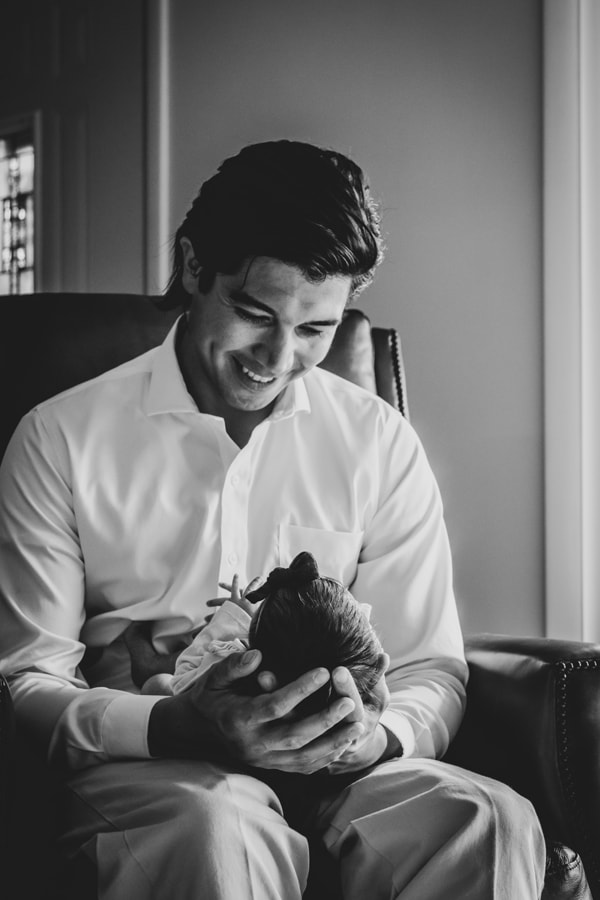 Father lovingly cradles sleeping newborn in tender black and white newborn portrait, Madison Wisconsin