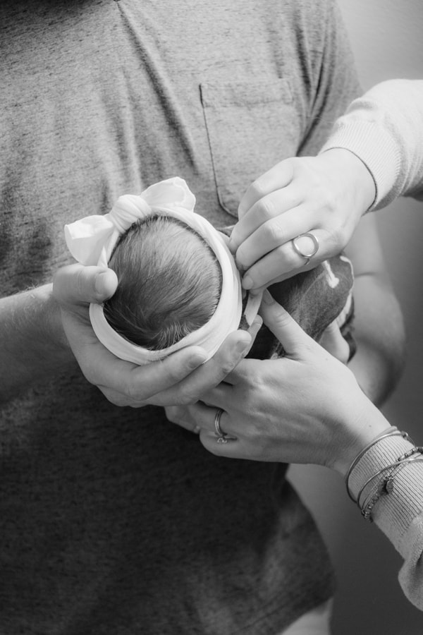 Tender newborn portrait showing protective parents' hands cradling sleeping baby in Madison, Wisconsin photography session