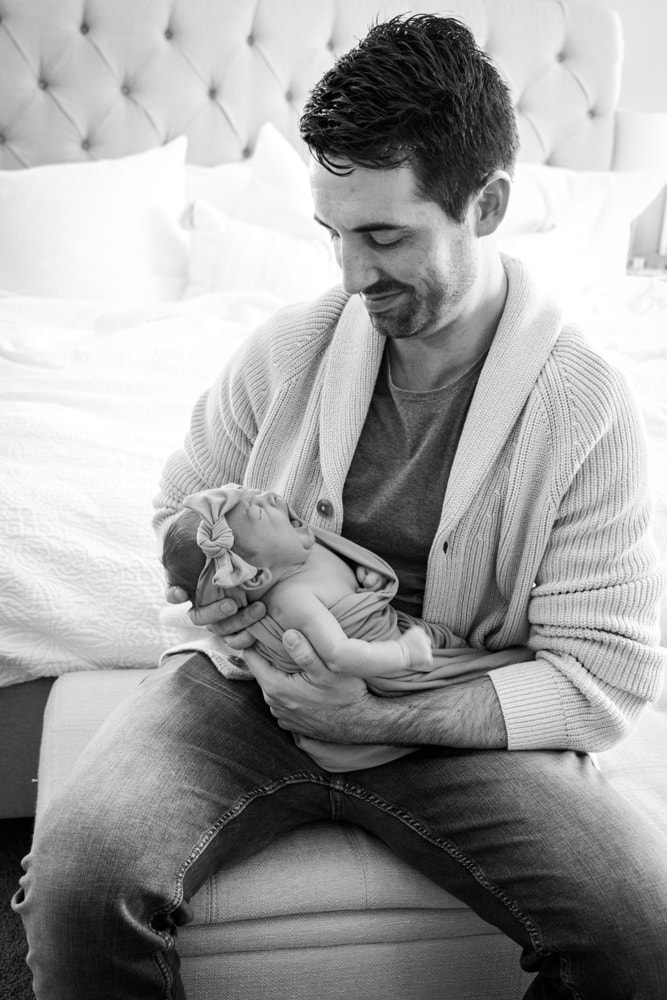 Tender father cradles sleeping newborn in intimate black and white newborn portrait, Madison, Wisconsin