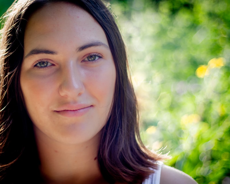 Confident brunette senior smiling in golden sunlight among green trees, Madison Wisconsin senior portrait photography